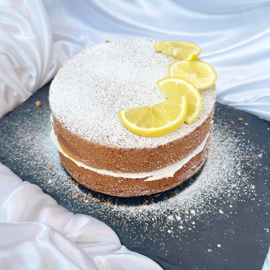 Two-layer cake with lemon slices on a dark surface